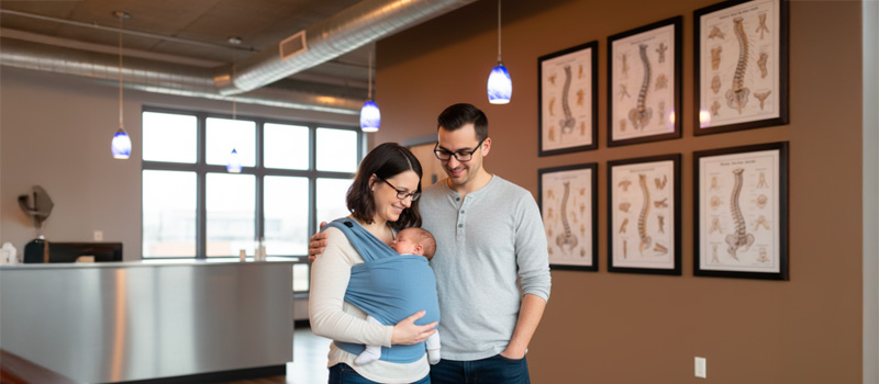 A calm infant being held by parents at Cafe of Life Longmont, receiving gentle pediatric chiropractic support for baby reflux symptoms
